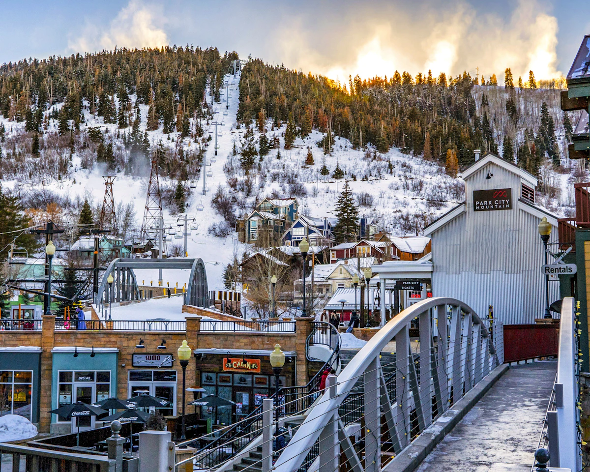 A snowy mountain resort town in winter, low buildings lining a street beneath white ski slopes