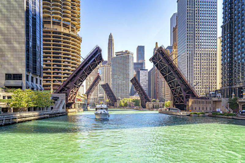 A river cruise boat passing raised bridges on the Chicago River with Marina City in view