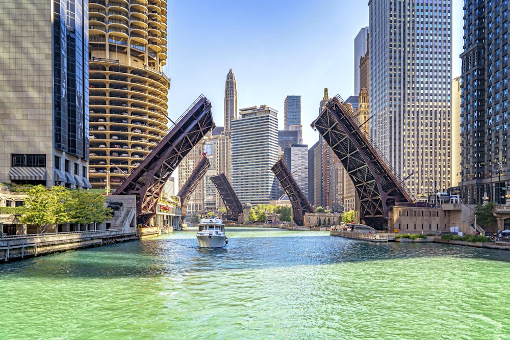 weißes und blaues Boot tagsüber auf dem Wasser in der Nähe von Hochhäusern