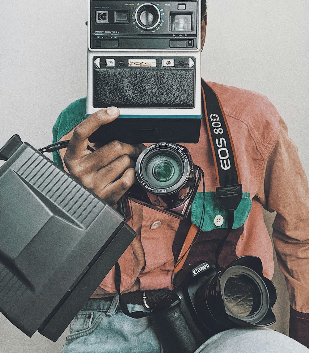 person in orange jacket holding black and gray camera