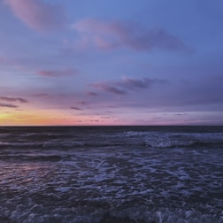 A serene ocean view with rolling waves under a soft blue sky at dusk.