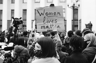 grayscale photo of people holding a white and black printed banner