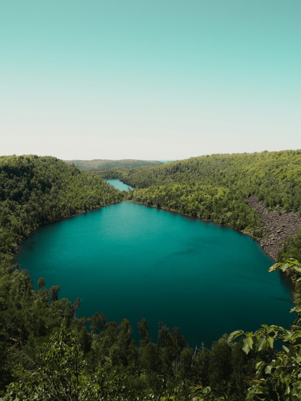 green lake surrounded by green trees during daytime