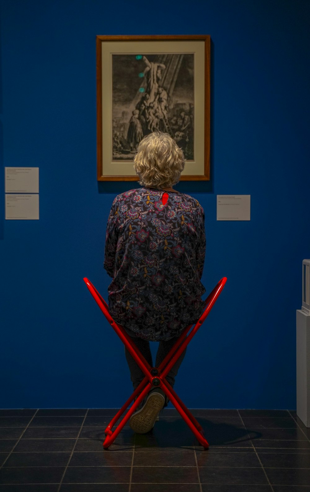 woman in black and green floral long sleeve shirt sitting on red wooden chair