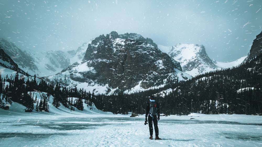 person in black jacket and black pants standing on snow covered ground during daytime