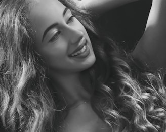 A black and white portrait of a woman laughing naturally in soft, diffused light.