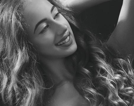 A black and white portrait of a woman laughing softly in natural light.