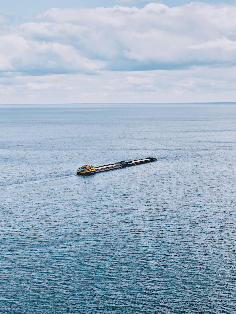 barco amarillo y negro en el mar bajo nubes blancas durante el día