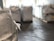 Large industrial sacks are positioned in a warehouse with a focus on one sack in the foreground and more sacks blurred in the background. The setting appears to be indoors with soft lighting, creating a sense of a spacious storage facility.