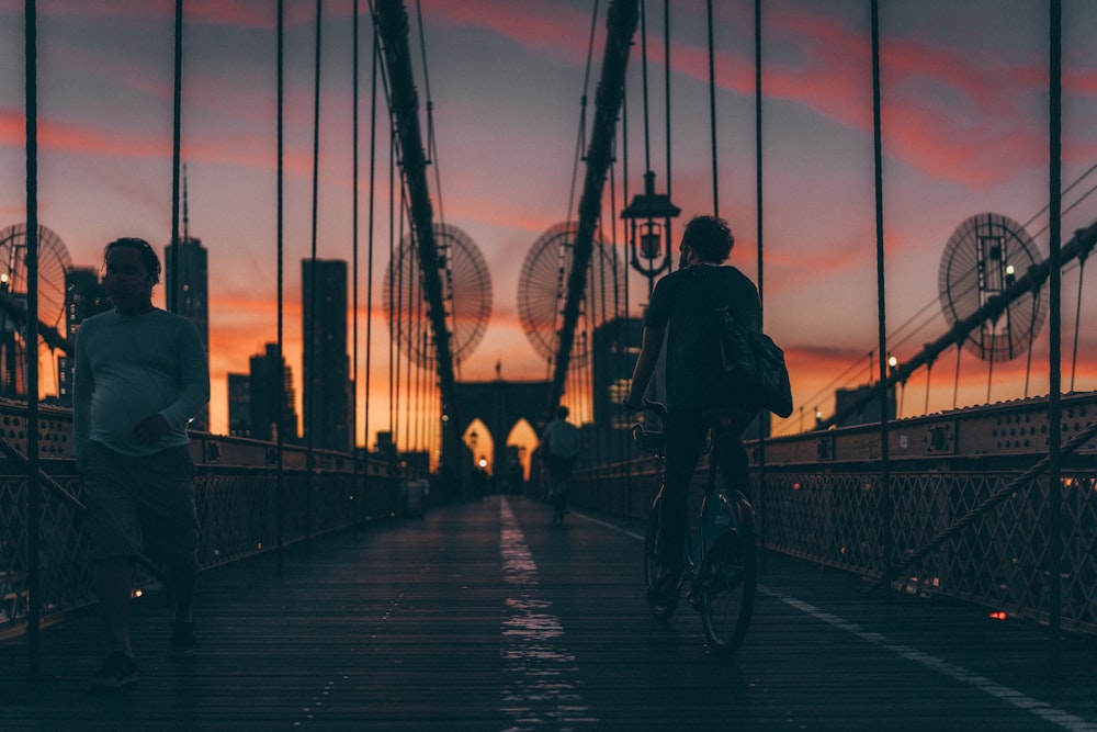 silhouette of people walking on bridge during sunset