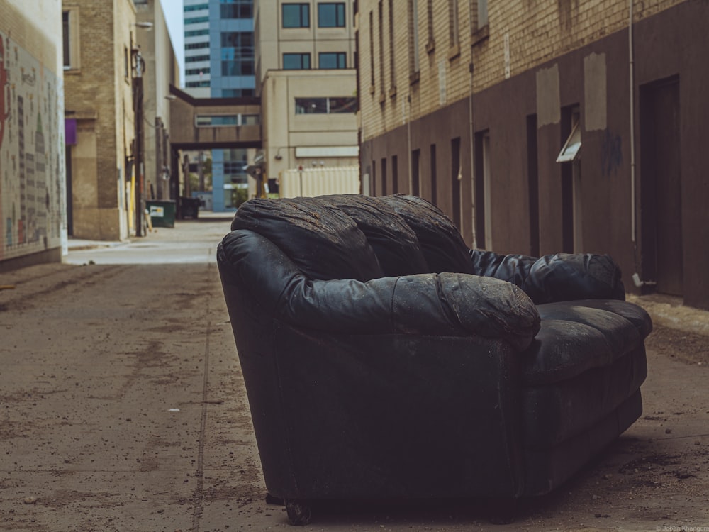 black leather couch beside brown brick wall