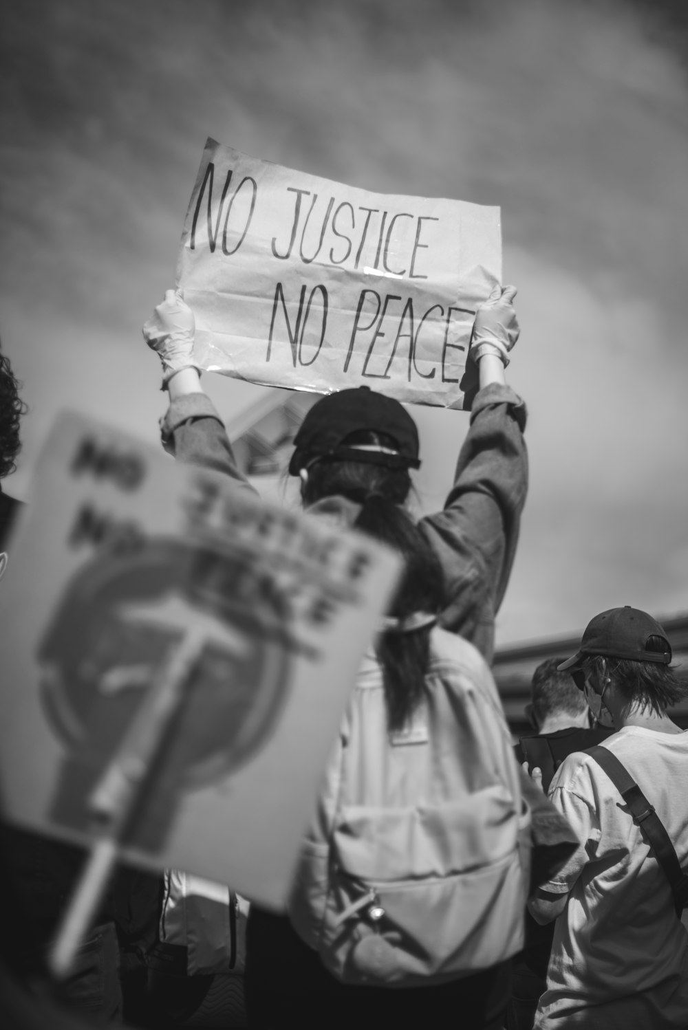 grayscale photo of man in white shirt holding white and black signage