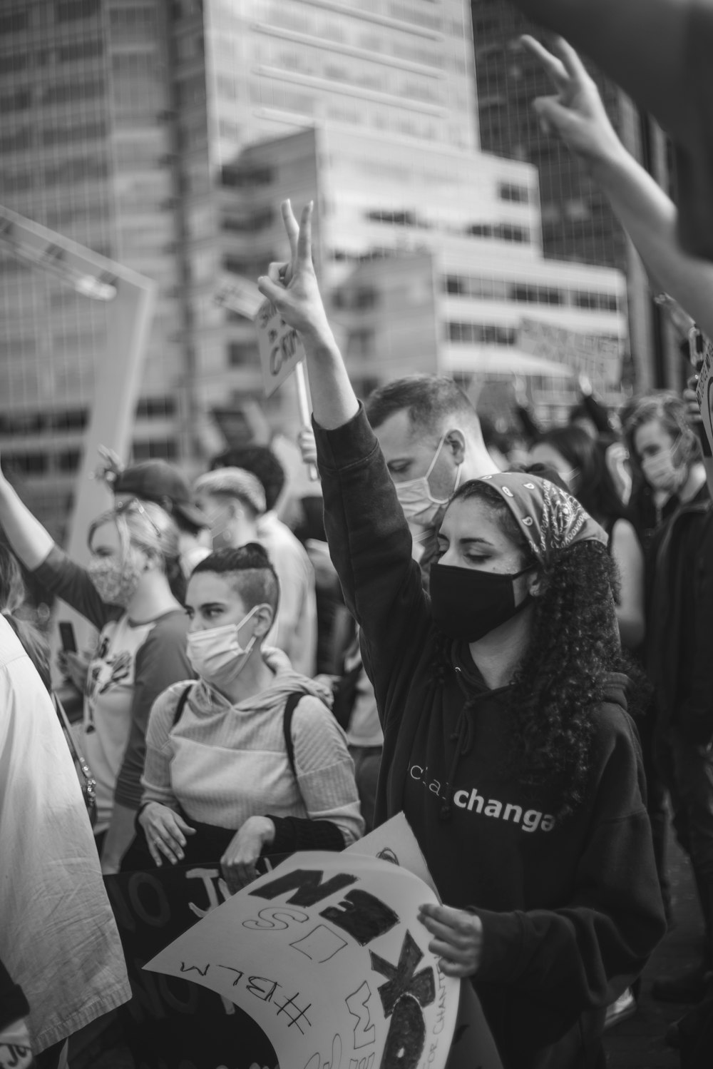 grayscale photo of man in black jacket raising his hands