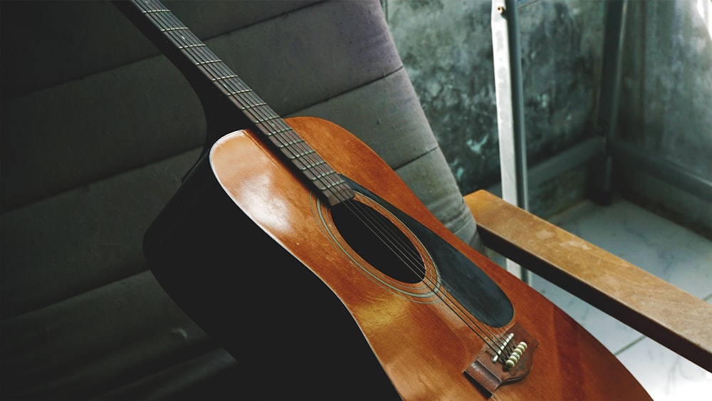 brown acoustic guitar on black sofa