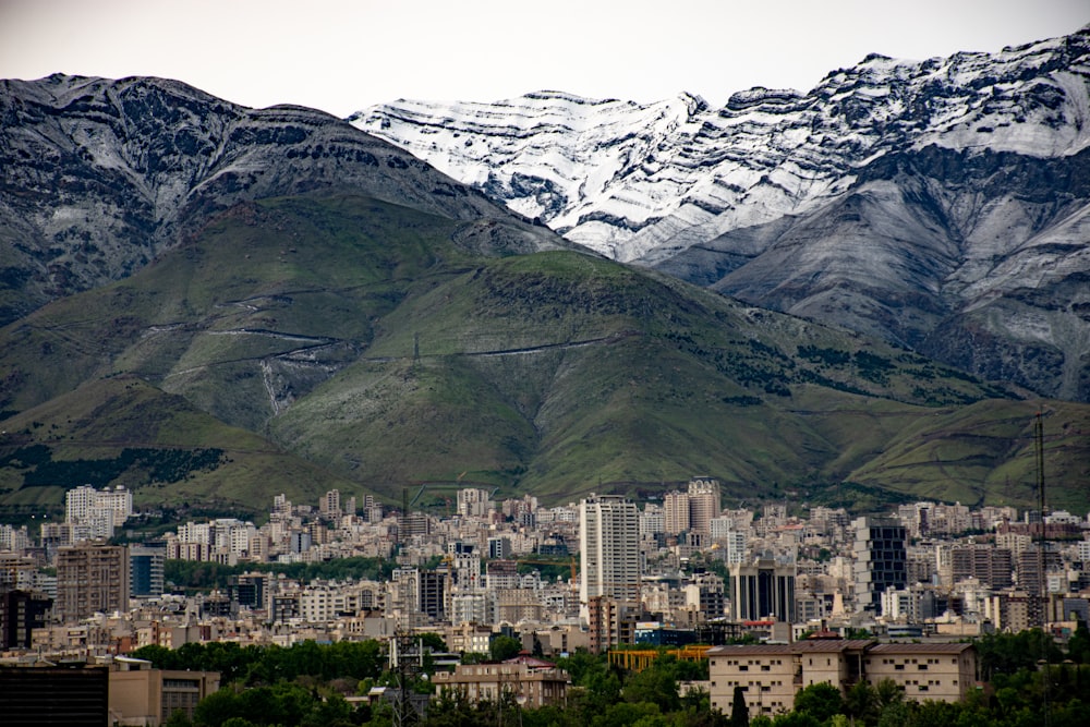 city buildings near green mountain during daytime