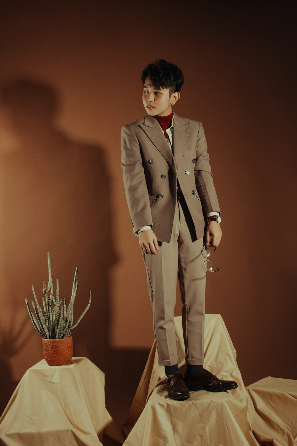 man in brown suit standing beside brown wooden table