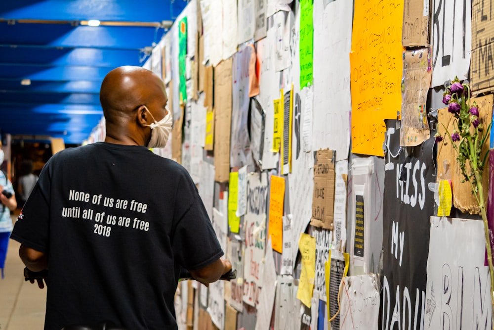 man in black crew neck t-shirt standing beside yellow and white wall