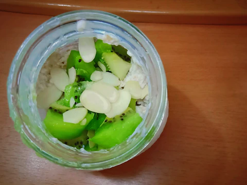 A jar of overnight oats with layers of yogurt, granola, and mixed fruits