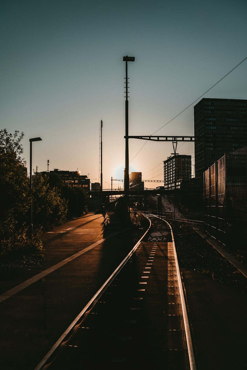 train rail near city buildings during sunset