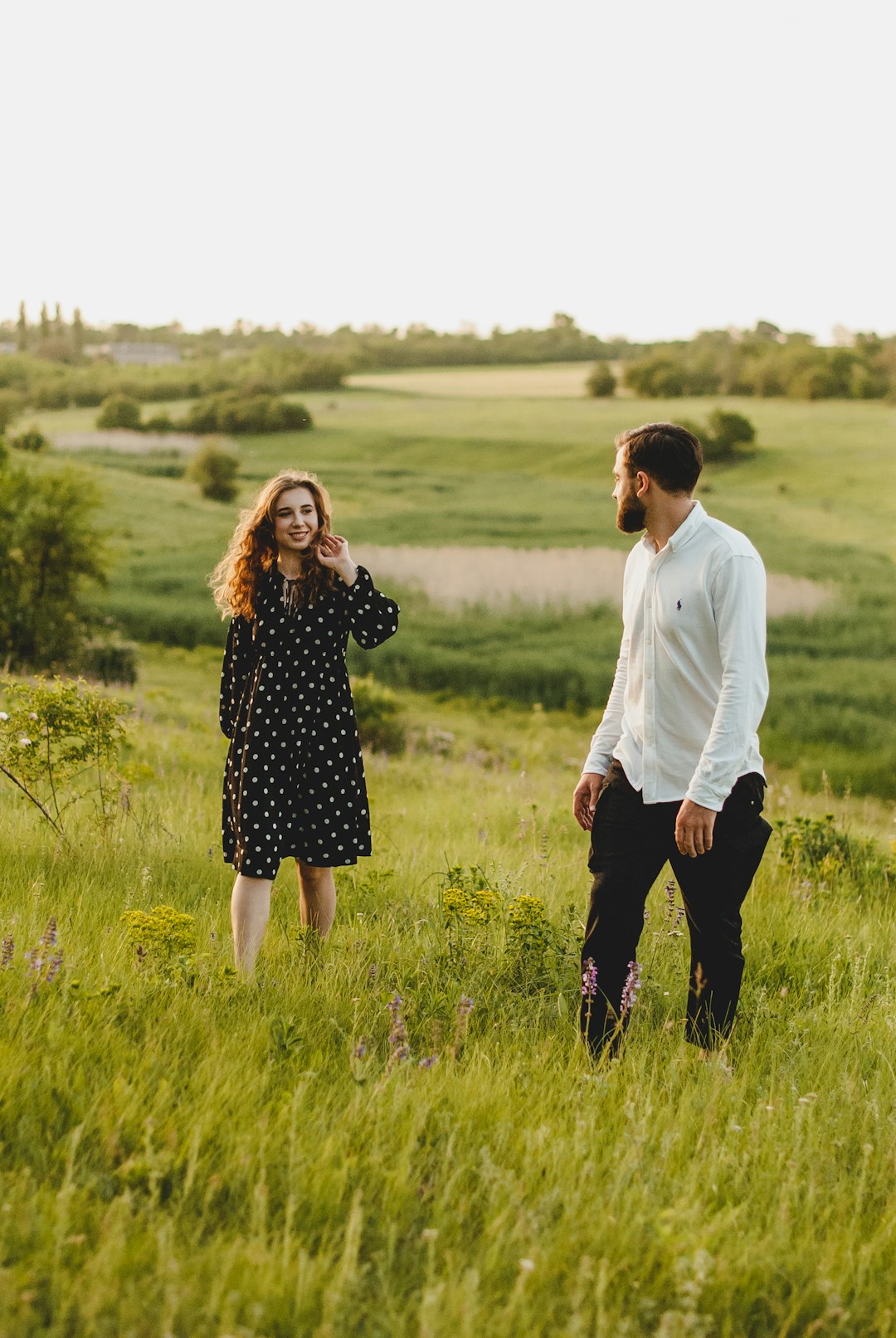 man and woman holding hands while walking on green grass field during daytime