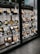 A display window with neatly arranged plastic food models representing various Japanese dishes. The models are placed on shelves, each accompanied by a label with descriptions and prices. The setup is in a traditional Japanese style, featuring wooden frames and a tiled roof.