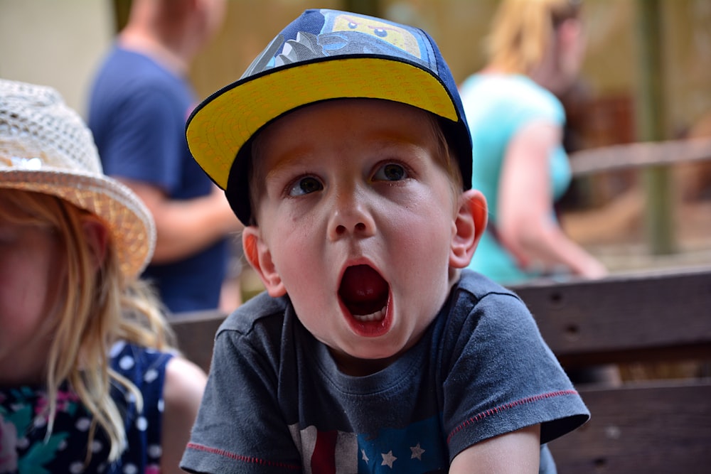 boy in blue crew neck t-shirt wearing blue and white cap