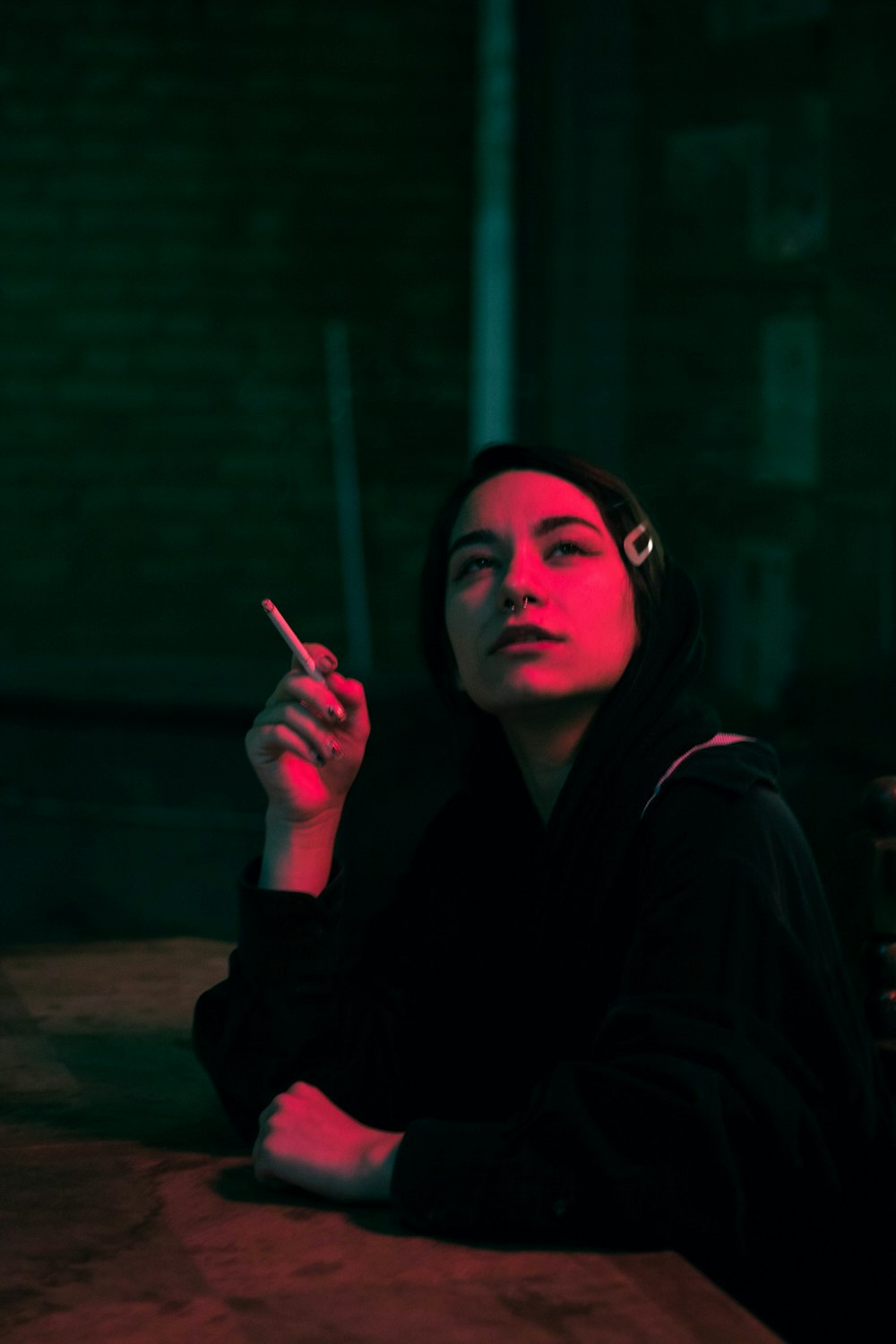 Frau in schwarzem Kapuzenpulli raucht Zigarette