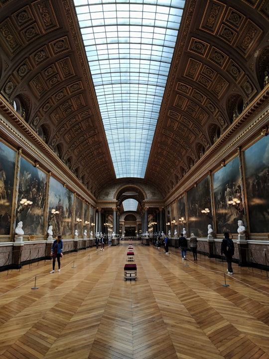 people walking on brown and white floor tiles in Palace of Versailles France