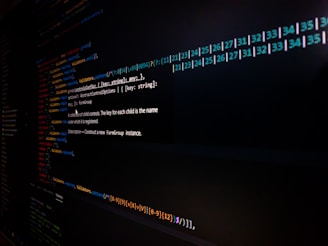 Lines of code are displayed on a computer screen, featuring syntax highlighting with different colors to distinguish functions, variables, and annotations. The image is somewhat dark, focusing on the brightly colored text on a black background.