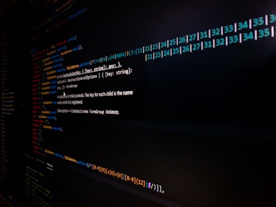 Lines of code are displayed on a computer screen, featuring syntax highlighting with different colors to distinguish functions, variables, and annotations. The image is somewhat dark, focusing on the brightly colored text on a black background.