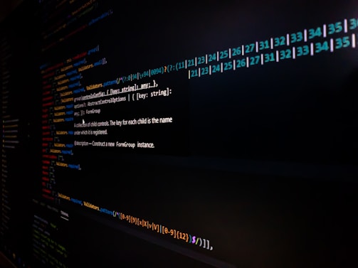 Lines of code are displayed on a computer screen, featuring syntax highlighting with different colors to distinguish functions, variables, and annotations. The image is somewhat dark, focusing on the brightly colored text on a black background.