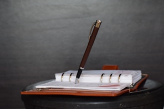 brown and white click pen on white notebook