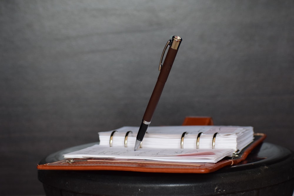 Bolígrafo de clic marrón y blanco en cuaderno blanco