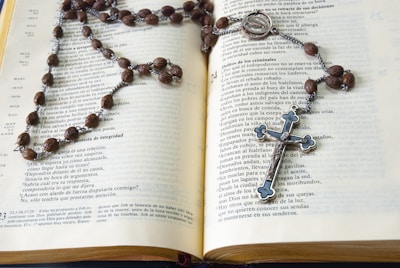 silver cross pendant necklace on book page