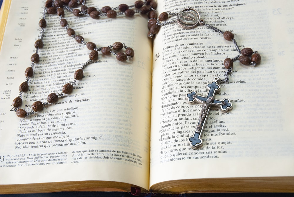 silver cross pendant necklace on book page