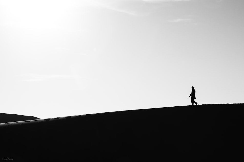 silhouette of person walking on top of the hill