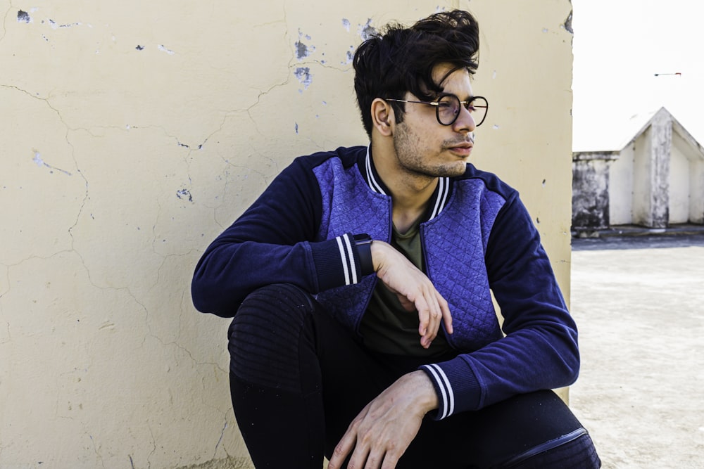 man in blue sweater and black pants sitting on blue chair