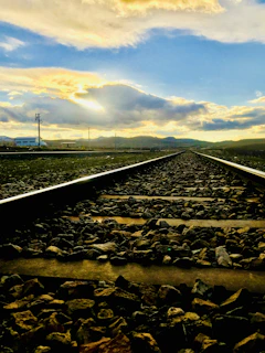 A modern railway track extending into the horizon with mountains in the distance during sunrise.