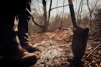 person in brown pants and brown boots holding brown wooden stick
