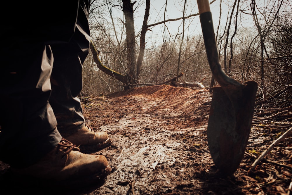 person in brown pants and brown boots holding brown wooden stick