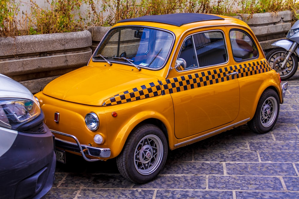 yellow car parked beside gray wall