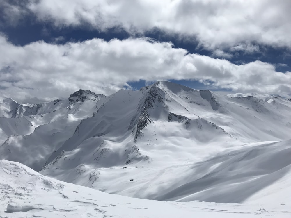 snow covered mountain under white clouds and blue sky during daytime