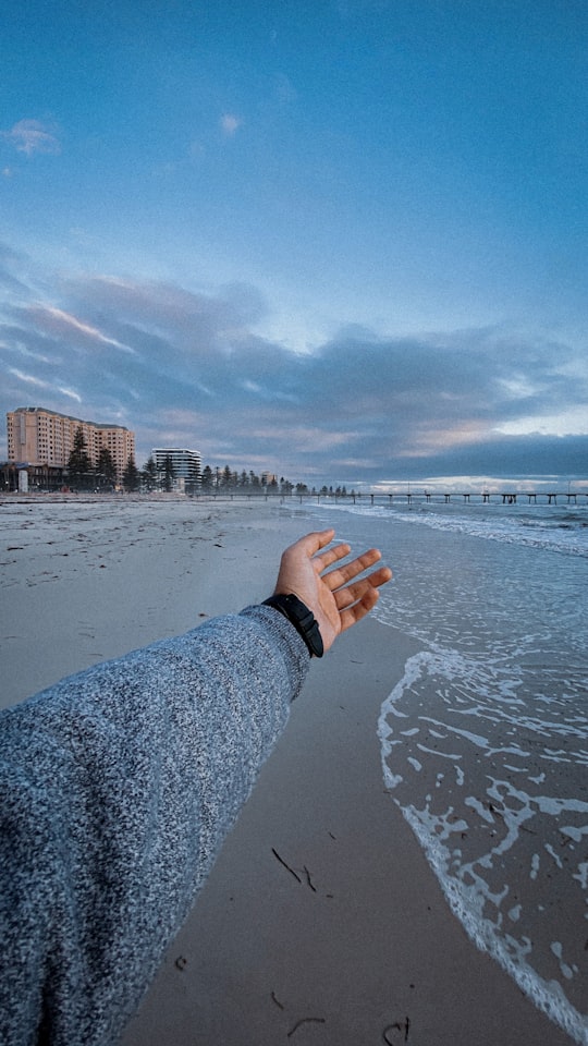 person in gray long sleeve shirt standing on gray sand near body of water during daytime in Adelaide Australia