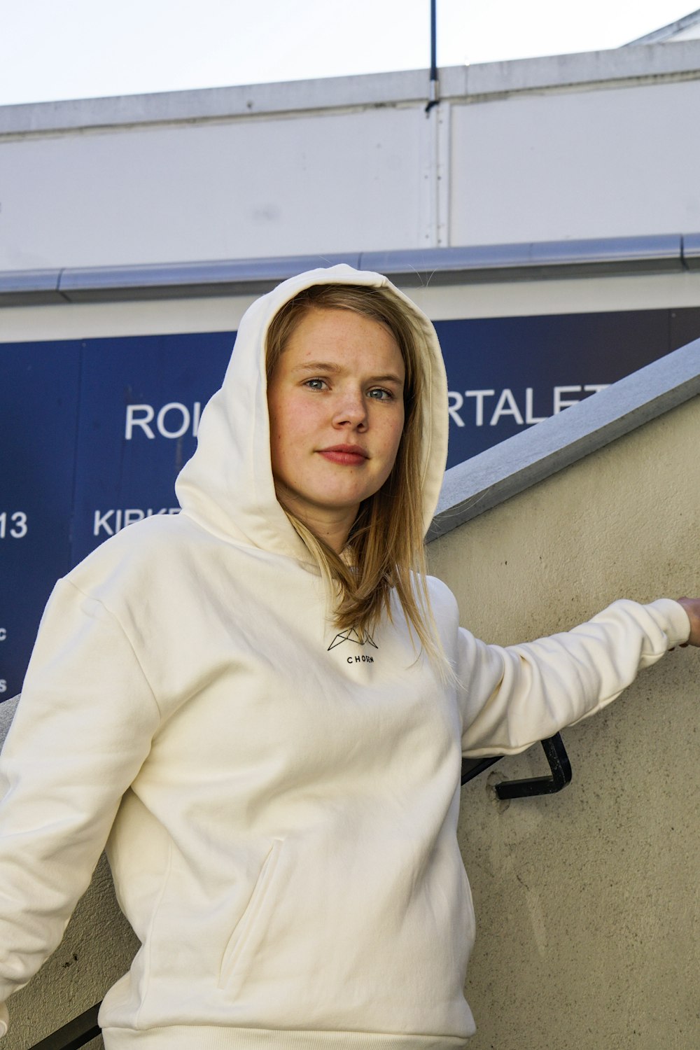 woman in white hoodie standing near blue and white wall