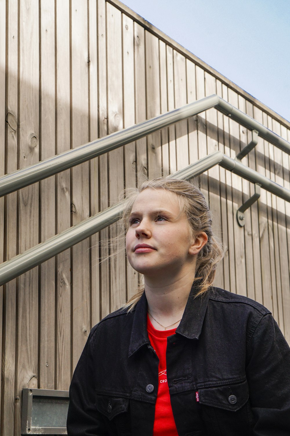 woman in black jacket standing near gray metal fence