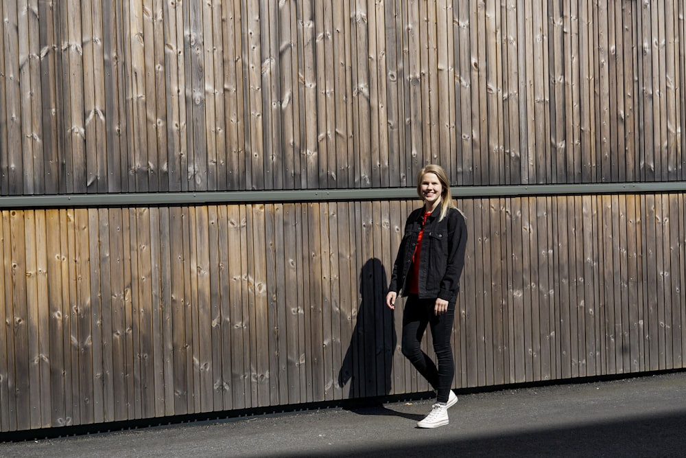 woman in black jacket and black pants standing on gray asphalt road during daytime