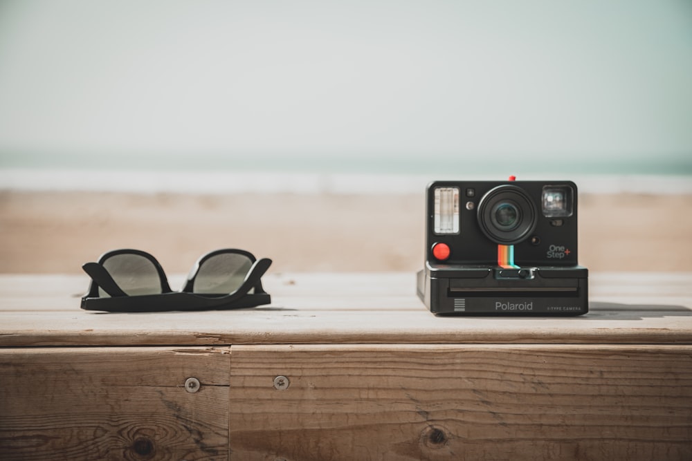 Macchina fotografica Polaroid nera e rossa su tavolo di legno marrone