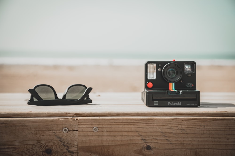 schwarz-rote Polaroidkamera auf braunem Holztisch