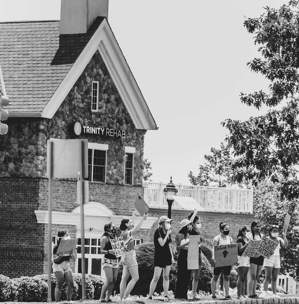 grayscale photo of people standing near building