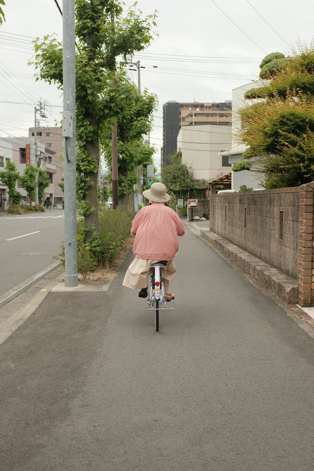 man in red dress shirt riding bicycle on road during daytime